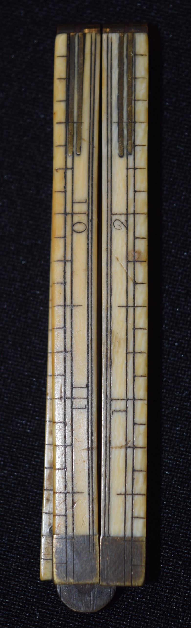 A VICTORIAN IVORY FOLDING RULE, formed with brass mounts and hinge. 30.5 cm wide.