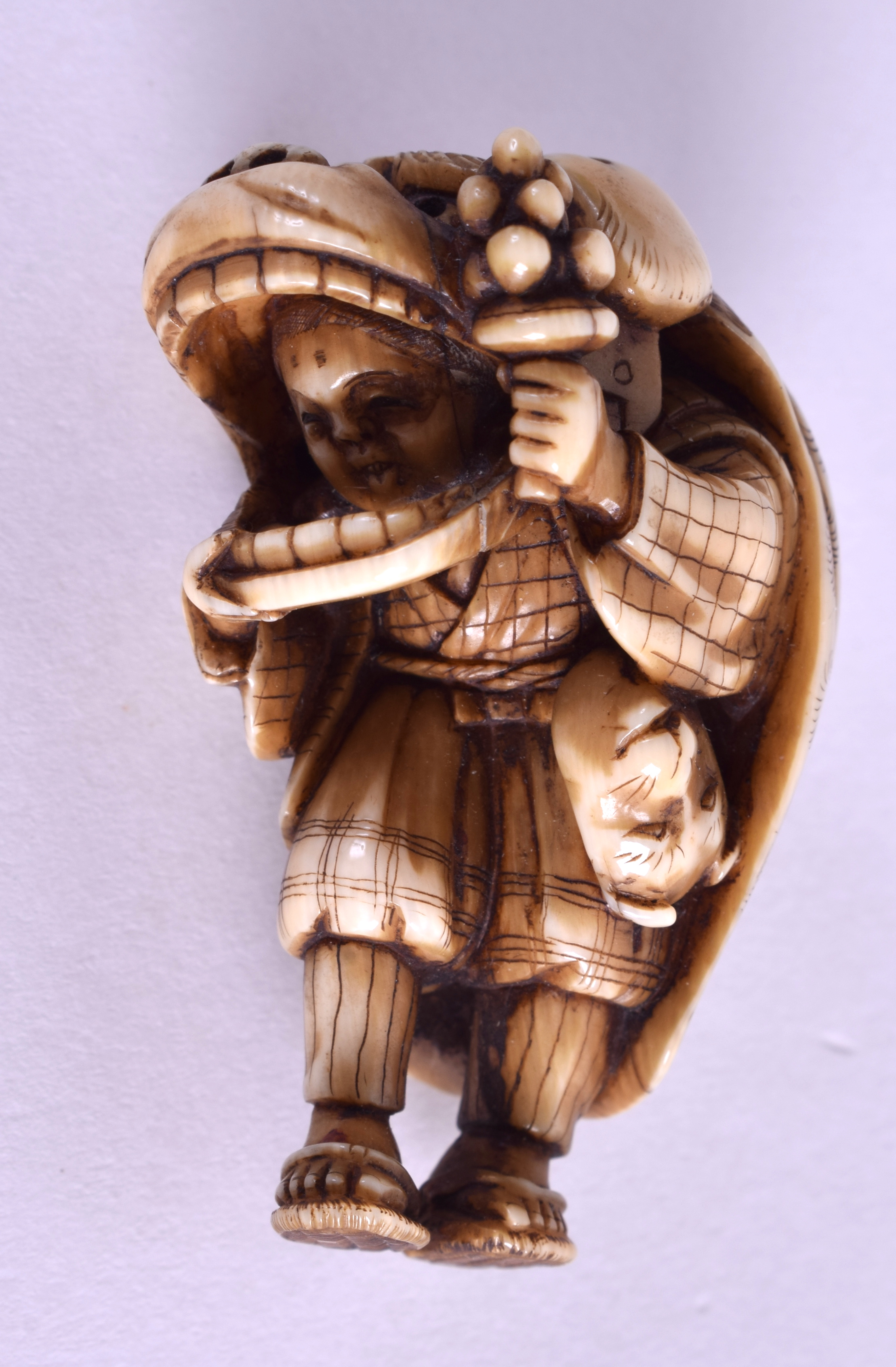 A 19TH CENTURY JAPANESE MEIJI PERIOD CARVED IVORY NETSUKE modelled as a male wearing a mask. 4.75 c