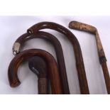 FOUR WALKING CANES OF VARYING FORM, together with an antique golf putter. (5)