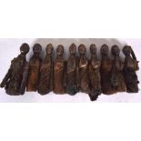 AN UNUSUAL PRIMATIVE FOLK ART TYPE WOODEN CARVING, in the form of ten conjoined figures in cloth ro