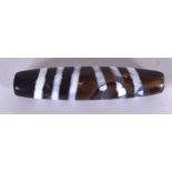 A CHINESE CARVED AGATE ZHU BEAD OR DZI BEAD, formed with swirling decoration. 6.8 cm long.