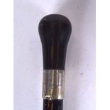 AN ANTIQUE WALKING CANE, formed with a bulbous wooden handle and silver collar. 89 cm long.