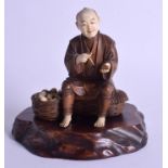 A 19TH CENTURY JAPANESE MEIJI PERIOD CARVED IVORY AND BOXWOOD SCHOLAR upon a hardwood stand. Figure