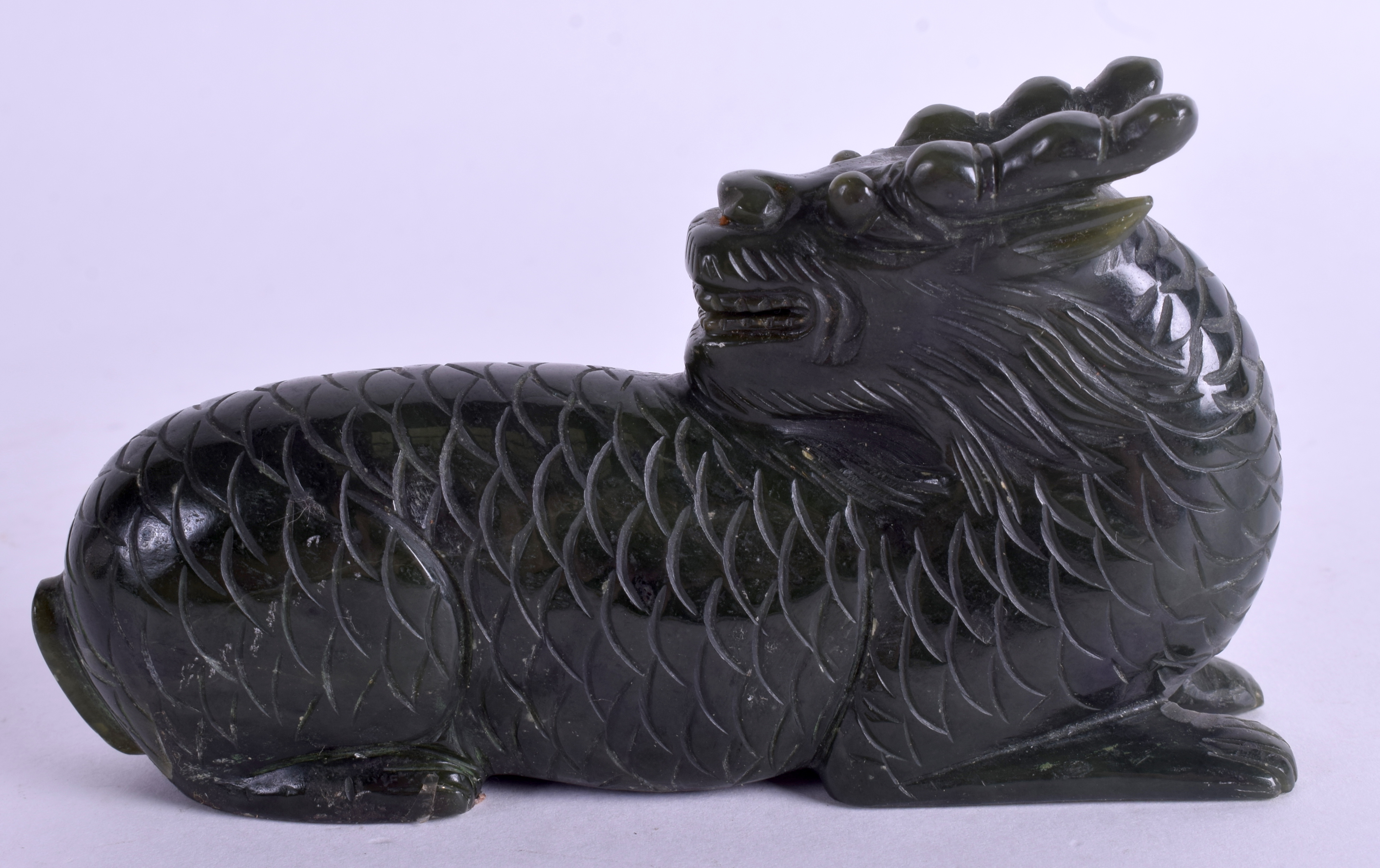 A CHINESE CARVED GREEN HARDSTONE BUDDHISTIC BEAST. 11 cm x 7 cm.
