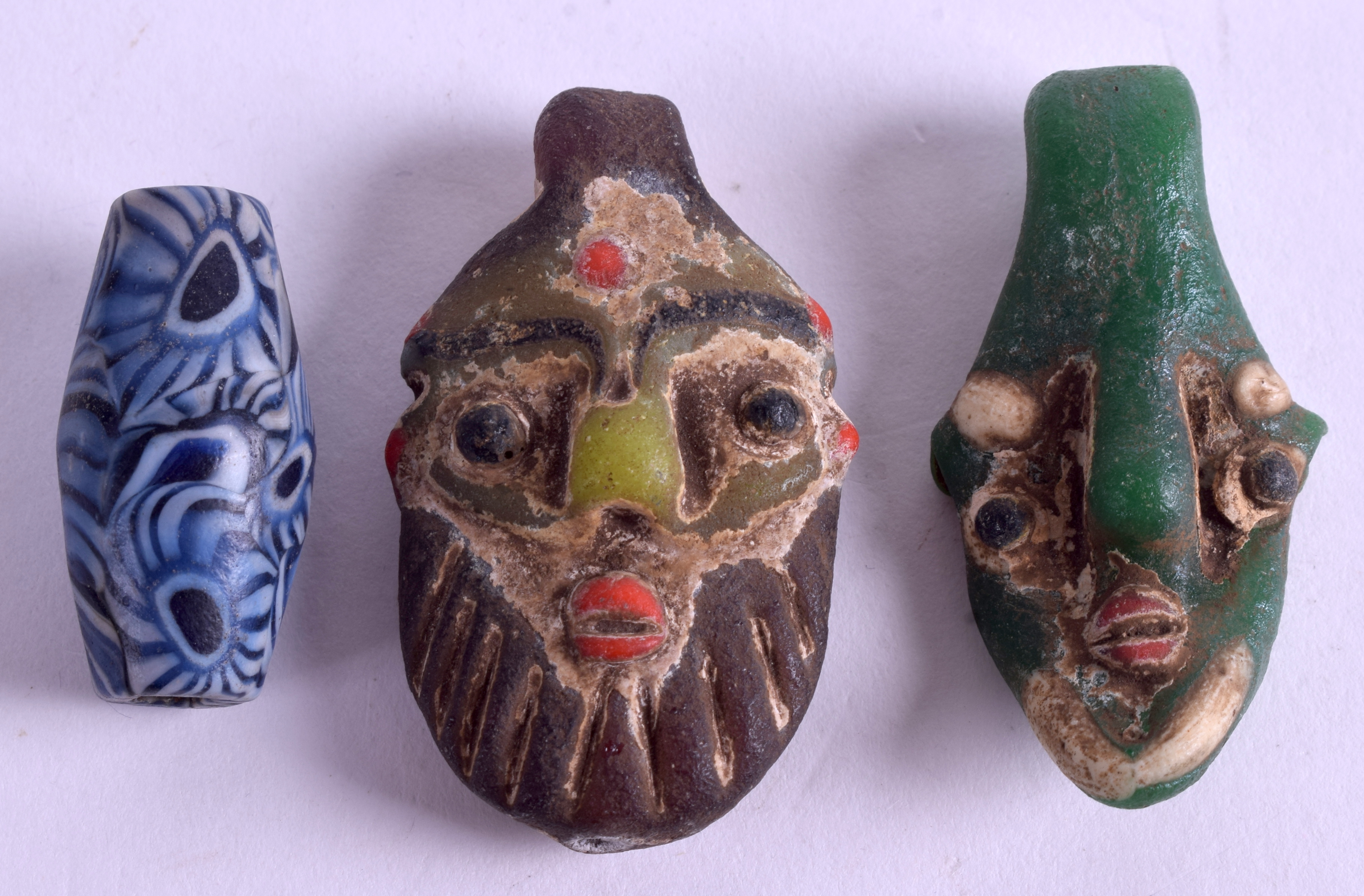 A PAIR OF UNUSUAL CONTINENTAL GLASS MASKS together with an agate toggle. (3)