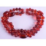 A 1920S RED AMBER TYPE NECKLACE. 290 grams. 110 cm long, largest bead 4 cm wide.