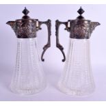 A PAIR OF ANTIQUE SILVER PLATED GLASS CLARET JUGS. 28 cm x 13 cm.