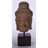 A CARVED SANDSTONE BUST, mounted upon a square form plinth. Total height 25 cm high.