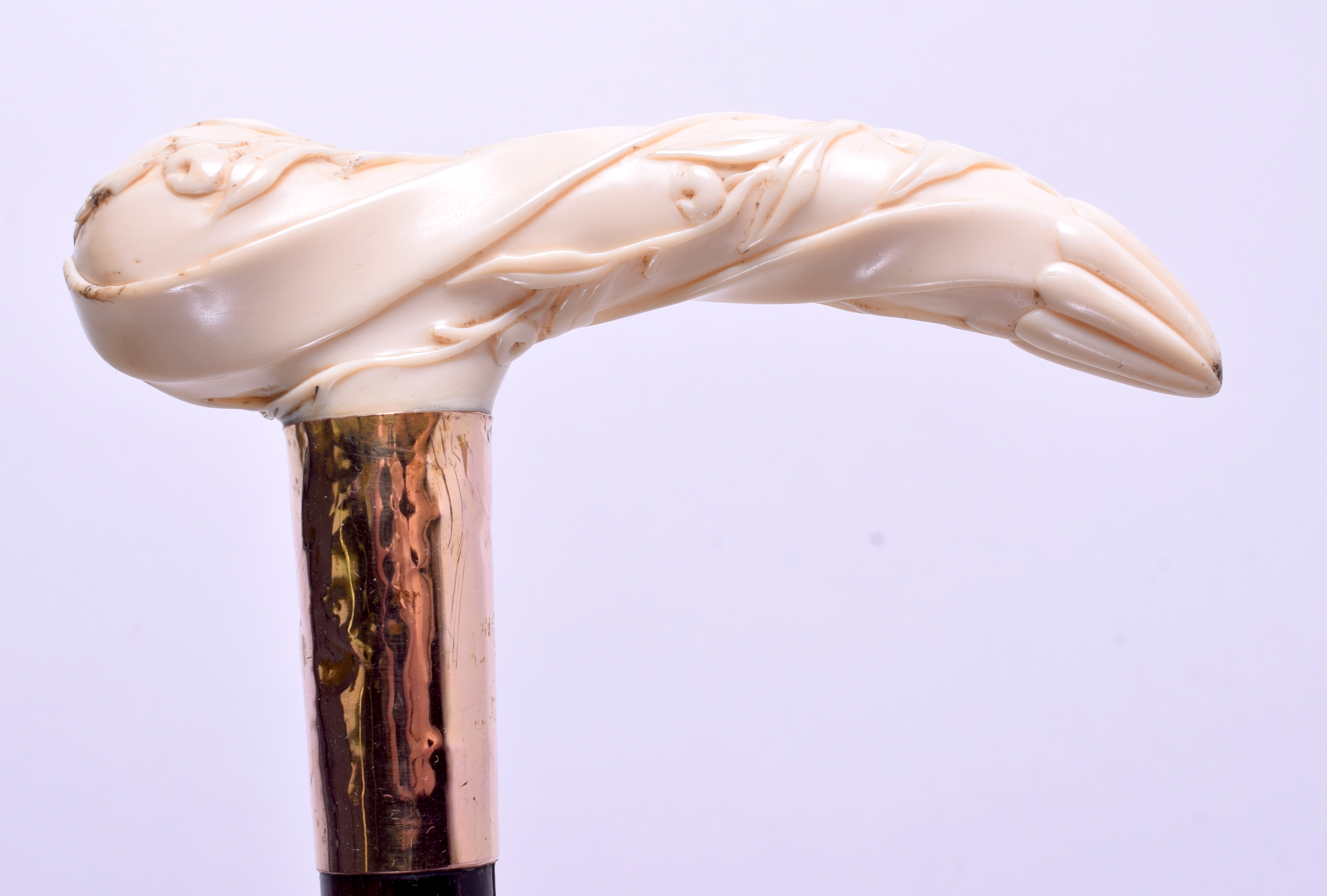 A 19TH CENTURY CARVED IVORY HANDLED WALKING CANE with yellow metal mounts. 90 cm long.