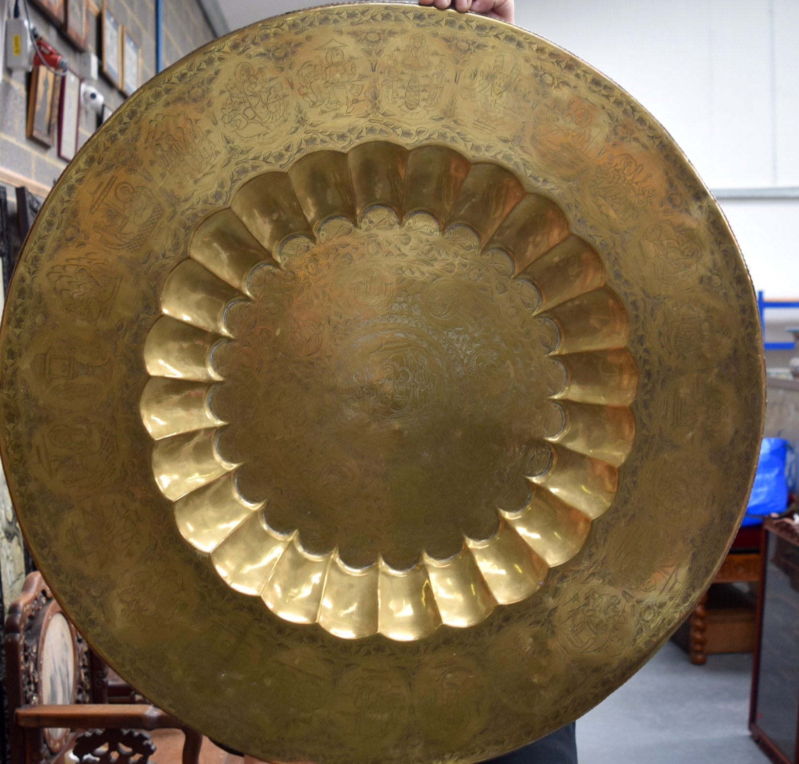 AN EARLY 20TH CENTURY INDIAN BRASS CHARGER, engraved with figures in various pursuits. 76 cm wide.