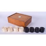 A BOXED SET OF ANTIQUE IVORY AND EBONY DRAUGHT PIECES. (qty)