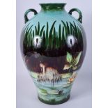 A LARGE ARTS AND CRAFTS FRENCH TWIN HANDLED VASE painted with storks roaming amongst the shallows.