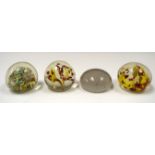 FOUR GLASS PAPERWEIGHTS, varying decoration. Largest 5.75 cm wide. (4)
