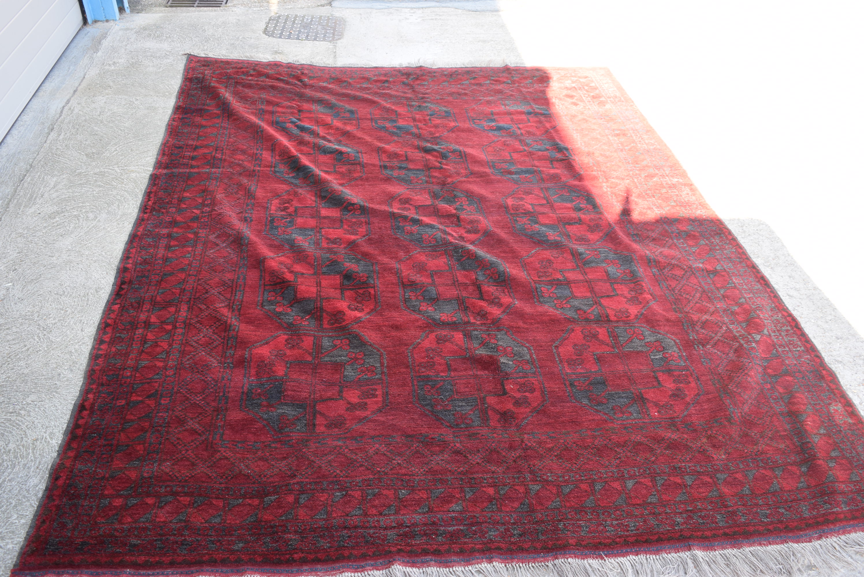 A LARGE RED GROUND AFGHAN RUG, decorated with symbols and motifs.316 cm x 250 cm.