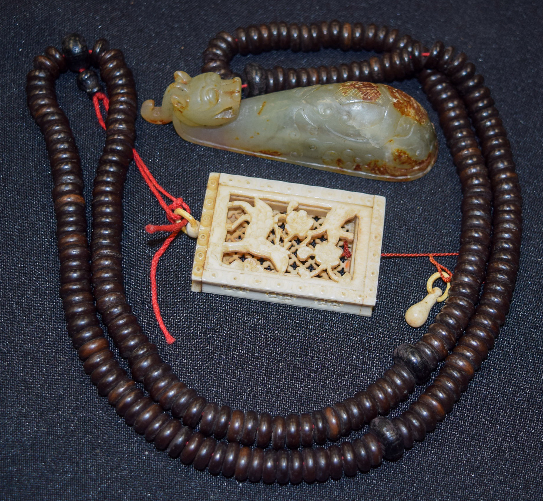 A CHINESE MUTTON JADE BELT HOOK, together with a wooden necklace with a carved ivory pendant. (2)