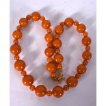 AN AMBER TYPE NECKLACE, formed with spherical beads and yellow metal clasp. 46 cm long.