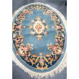 A 20TH CENTURY PALE BLUE GROUND OVAL SHAPED RUG, decorated with bold foliage. 183 cm x 125 cm.