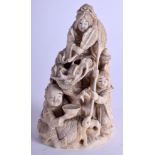 A 19TH CENTURY JAPANESE MEIJI PERIOD CARVED IVORY OKIMONO modelled with figures clambering over a d