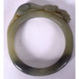A LARGE CHINESE GREEN JADE BANGLE, carved with a recumbent chilong clinging to the top. 12 cm x 11