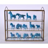 A COLLECTION OF FOURTEEN CHINESE BLUE GLAZED PORCELAIN HORSES, contained within a glass display cas