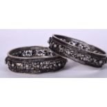 A PAIR OF WHITE METAL EASTERN BANGLES, decorated with animals. 7 cm wide.