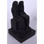 A RESIN FIGURE OF TWO SEATED EGYPTIANS, modelled upon a square plinth. 15 cm high.