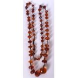 AN EARLY 20TH CENTURY LONG STRAND AMBER BEAD NECKLACE, formed with flattened facetted beads. 108 cm