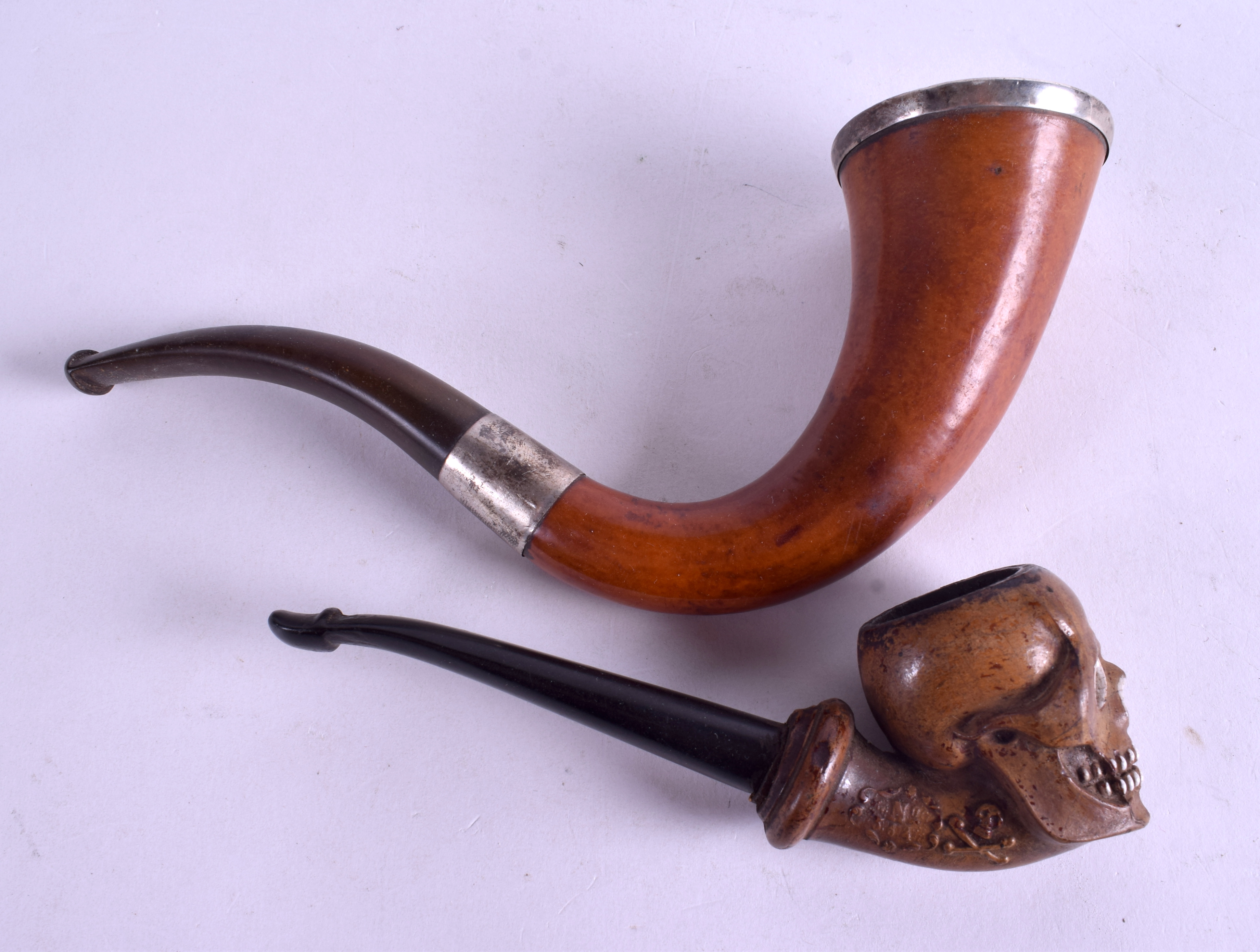 AN ANTIQUE CARVED MEERSCHAUM SKULL PIPE together with another similar. 11 cm & 16 cm long. (2)