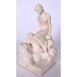 AN EARLY 20TH CENTURY PLASTER FIGURE OF A SEATED FEMALE, modelled upon rocks. 18 cm high.