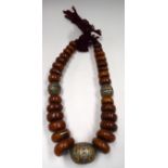 A MORROCAN AMBER AND ENAMELLED NECKLACE, formed with flattened beads. 64 cm long.