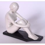 A EUROPEAN PORCELAIN FIGURINE IN THE FORM OF A FEMALE, modelled seated upon a rectangular base. 14