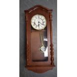 A WILLIAM WIDDOP WOODEN WALL CLOCK, with associated key and pendulum. 62.5 cm x 27 cm.