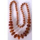 A 1920'S ART DECO AMBER NECKLACE, formed with flattened circular beads. 63 cm long and weight 52 gr