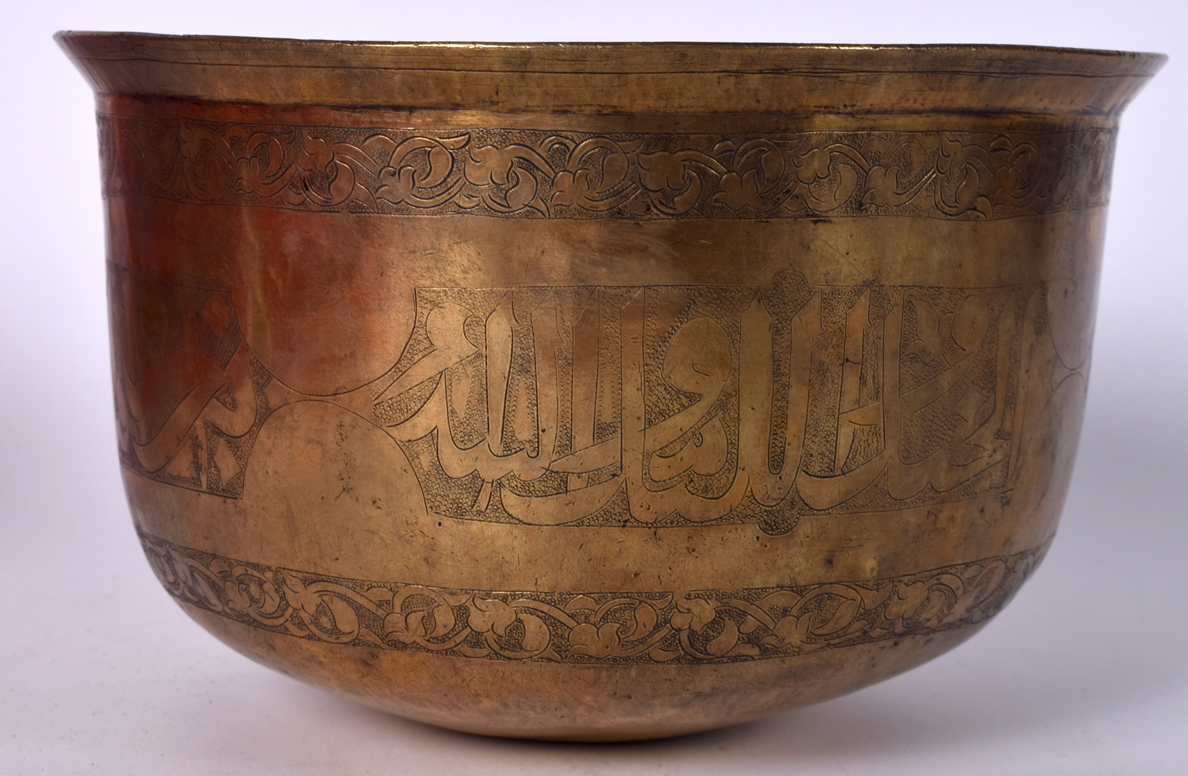 AN 18TH CENTURY ISLAMIC BRONZE BOWL, engraved with script within foliate banding. 13 cm x 22.5 cm.