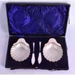 A PAIR OF CASED SILVER SHELL BUTTER DISHES with knives. Silver 4.2 oz. Shell 9 cm x 12 cm.