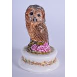 A MICHAEL SUTTY PORCELAIN FIGURINE OF AN OWL. Modelled upon a floral base. 8 cm high.