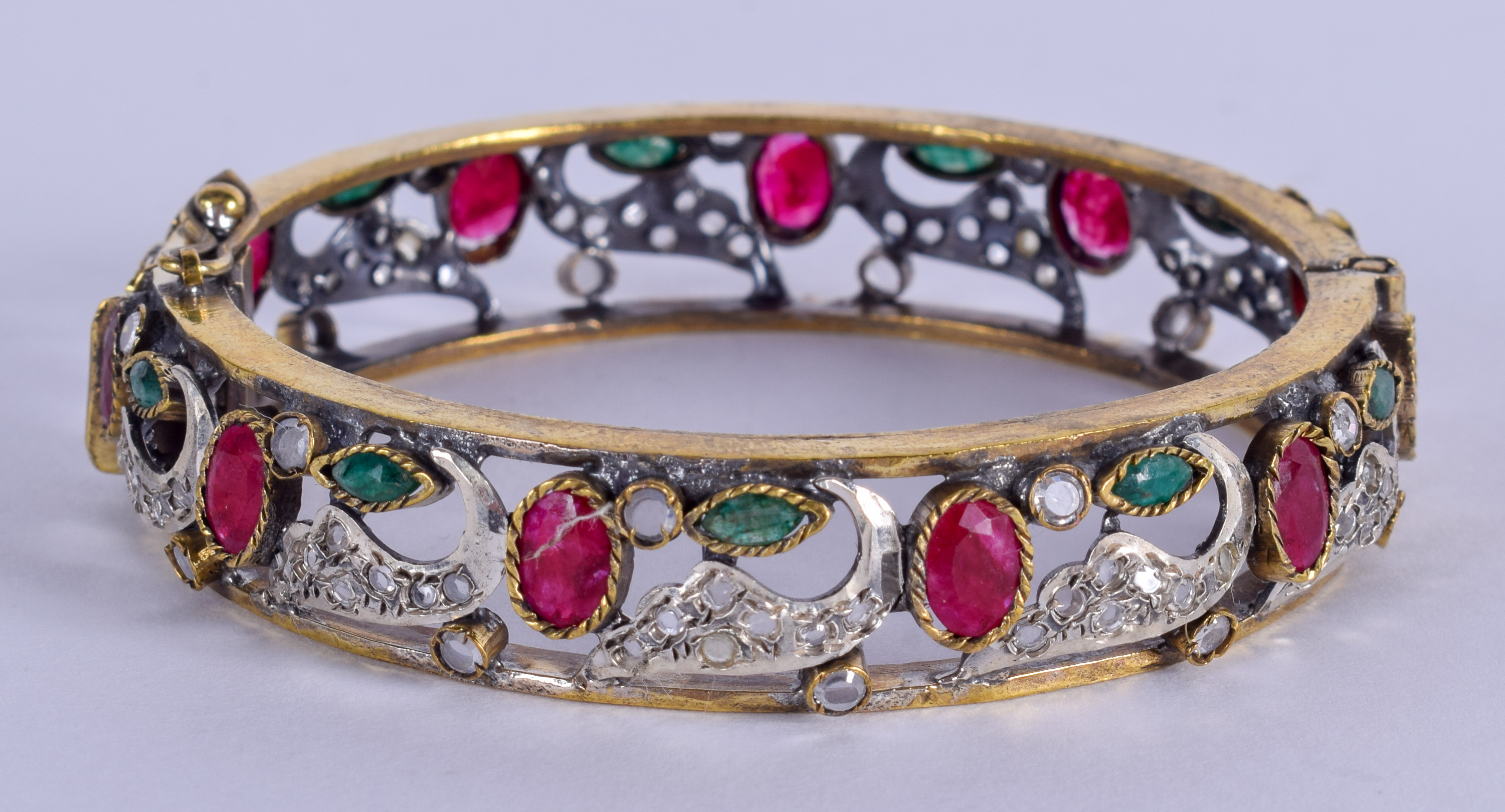 A VINTAGE GARNET AND EMERALD BANGLE. 7 cm wide.