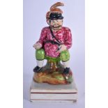 AN EARLY 19TH CENTURY PEARLWARE FIGURINE IN THE FORM OF FALSTAFF, modelled seated upon a tree stump