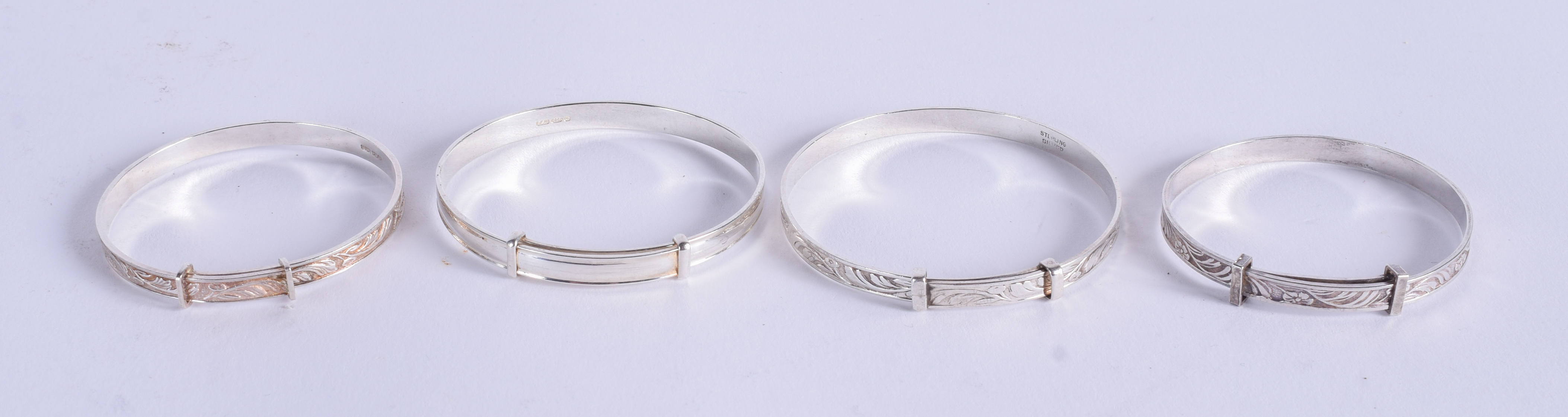 FOUR CHILDS SILVER BANGLES. 4.25 cm wide. (4)