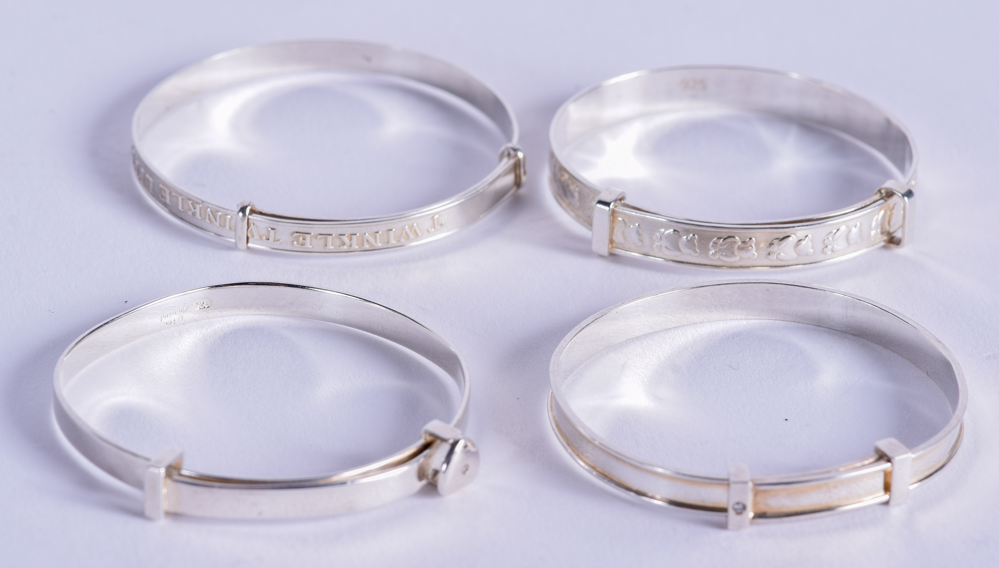 FOUR CHILDS SILVER BANGLES. 4.25 cm wide. (4)