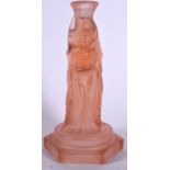 AN ART DECO PINK GLASS FIGURAL CANDLESTICK, formed with three semi clad females holding aloft an ur