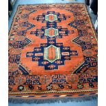 AN EARLY 20TH CENTURY BURNT ORANGE GROUND RUG, decorated with geometric motifs. 201 cm x 153 cm.