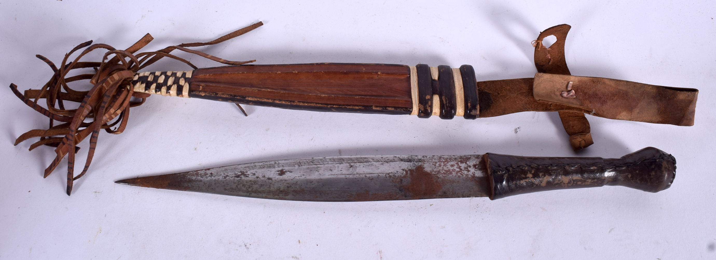 A WEST AFRICAN DAGGER, formed with leather scabbard. 33 cm.