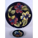 A MOORCROFT POTTERY DISH, together with a larger plate, each decorated with bold foliage. Largest 3