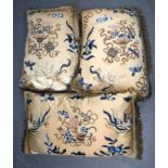 THREE EARLY 20TH CENTURY CHINESE SILKWORK PILLOWS depicting beasts and objects. Largest 31 cm x 61