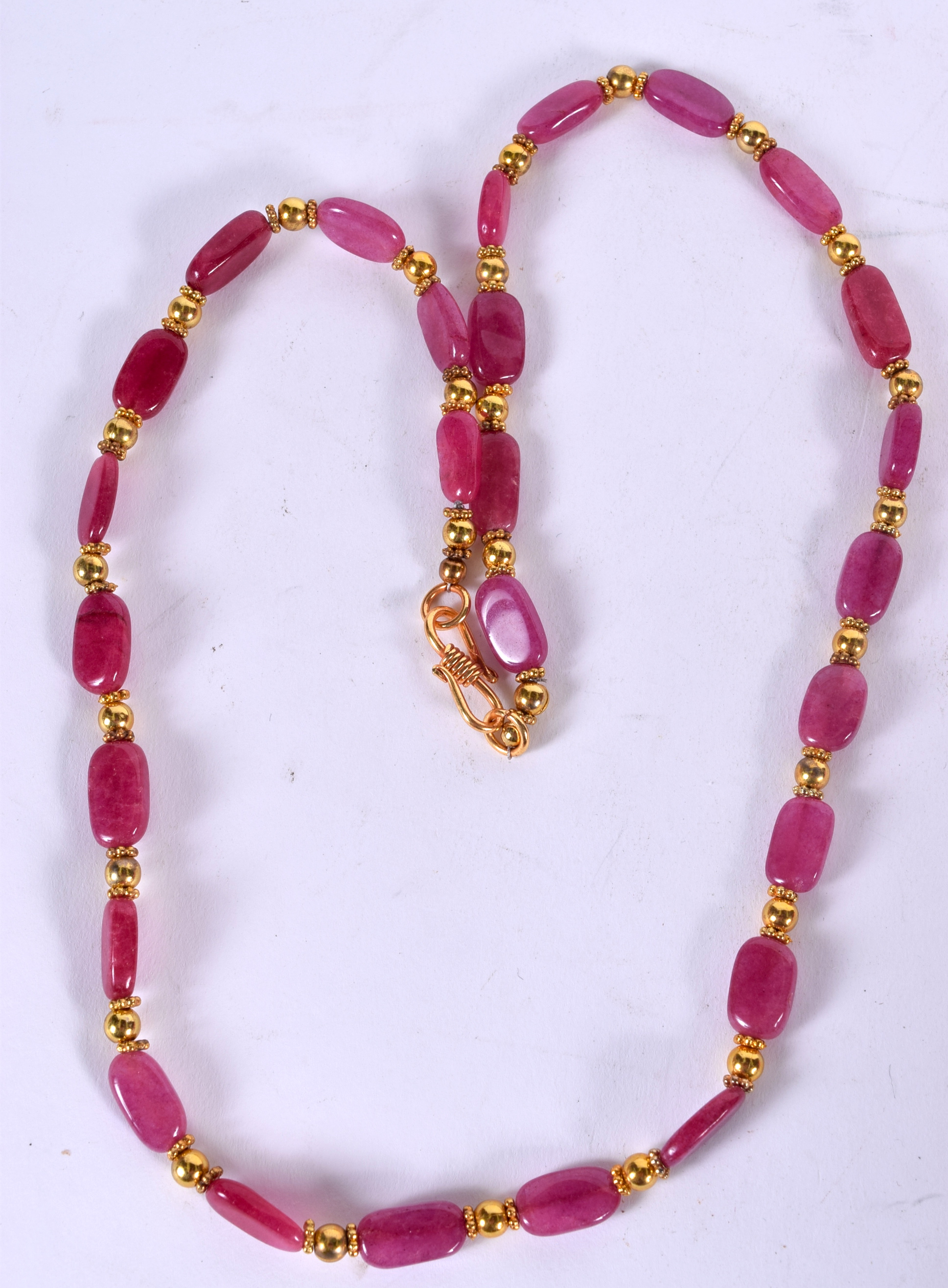 A PINK HARDSTONE NECKLACE, formed with yellow metal spacers. 42 cm long.