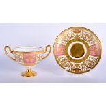 A MINTON TWO HANDLED PEDESTAL CUP AND SAUCER with rose pompadour ground with neo-classical raised g