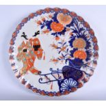 A LARGE 19TH CENTURY JAPANESE MEIJI PERIOD SCALLOPED IMARI CHARGER painted with two geisha within a