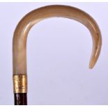 AN EARLY 20TH CENTURY BLOND RHINOCEROS HORN HANDLED WALKING STICK, formed with an 18ct gold plated