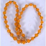 AN AMBER TYPE NECKLACE, formed with twisted beads and yellow metal spacers. 48 cm long.